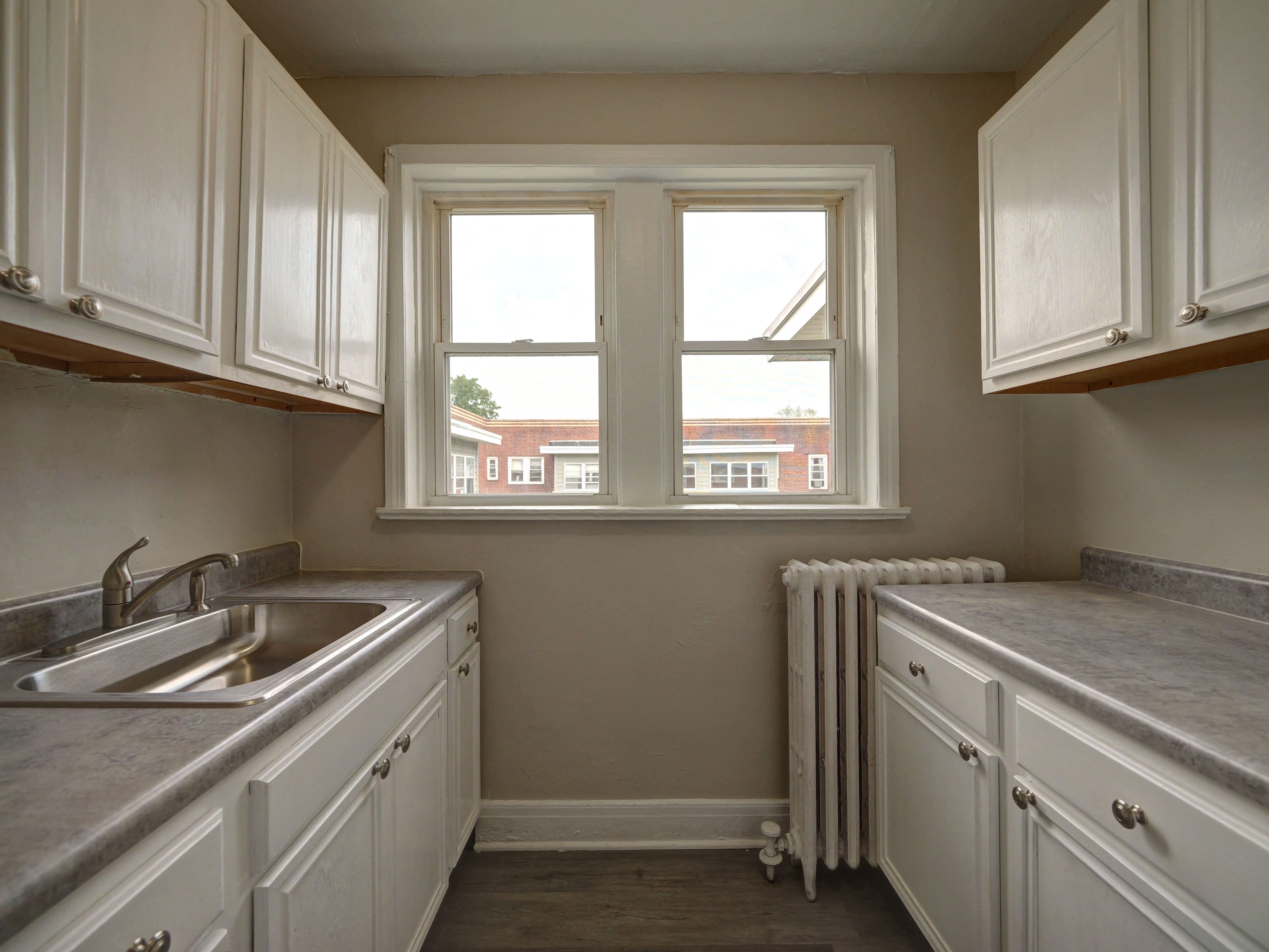 A kitchen with white cabinets and a window.
