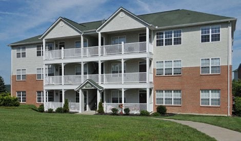 an apartment building with a large yard in front of it