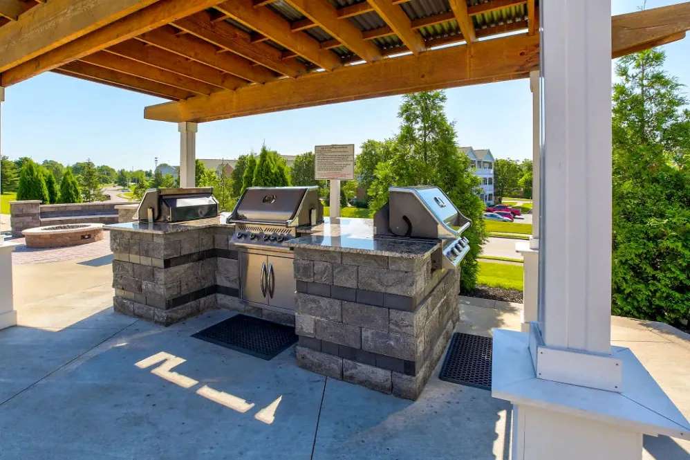 an outdoor grilling area with two bbqs on a patio