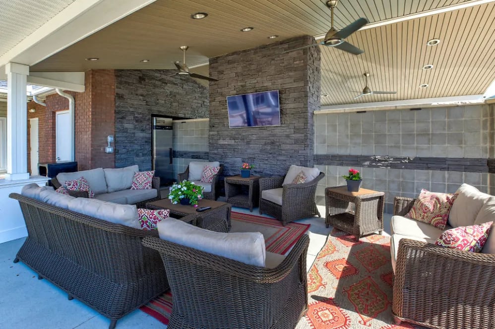 a covered patio with wicker furniture and a television