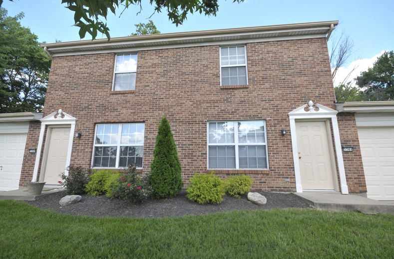 the front of a brick house with two white doors