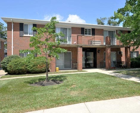 the front of a brick apartment building with a tree in the yard