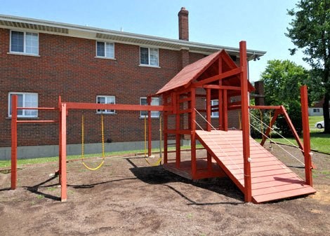 a red swing set in front of a brick building
