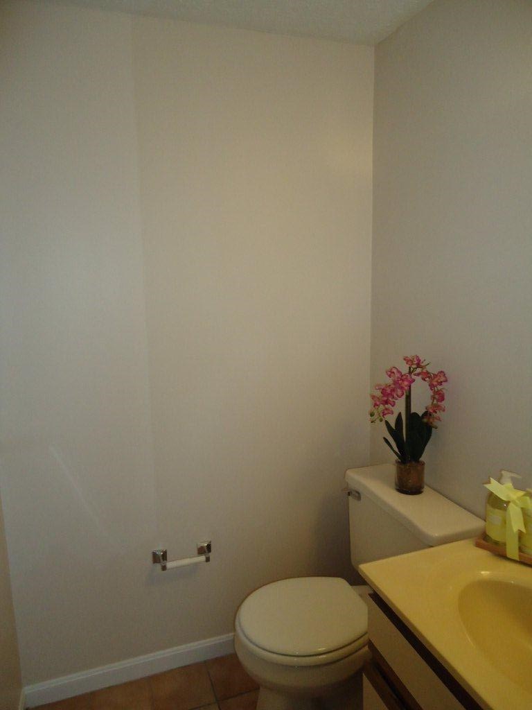 a bathroom with a toilet and a vase with flowers