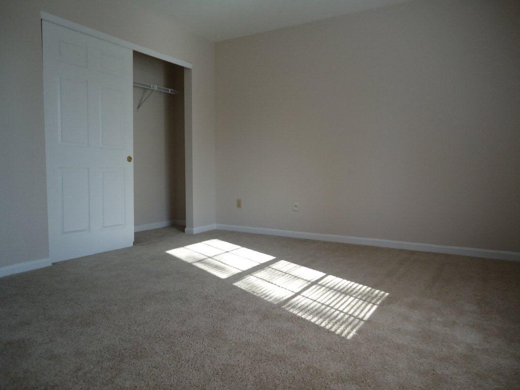 an empty room with a white door and carpet