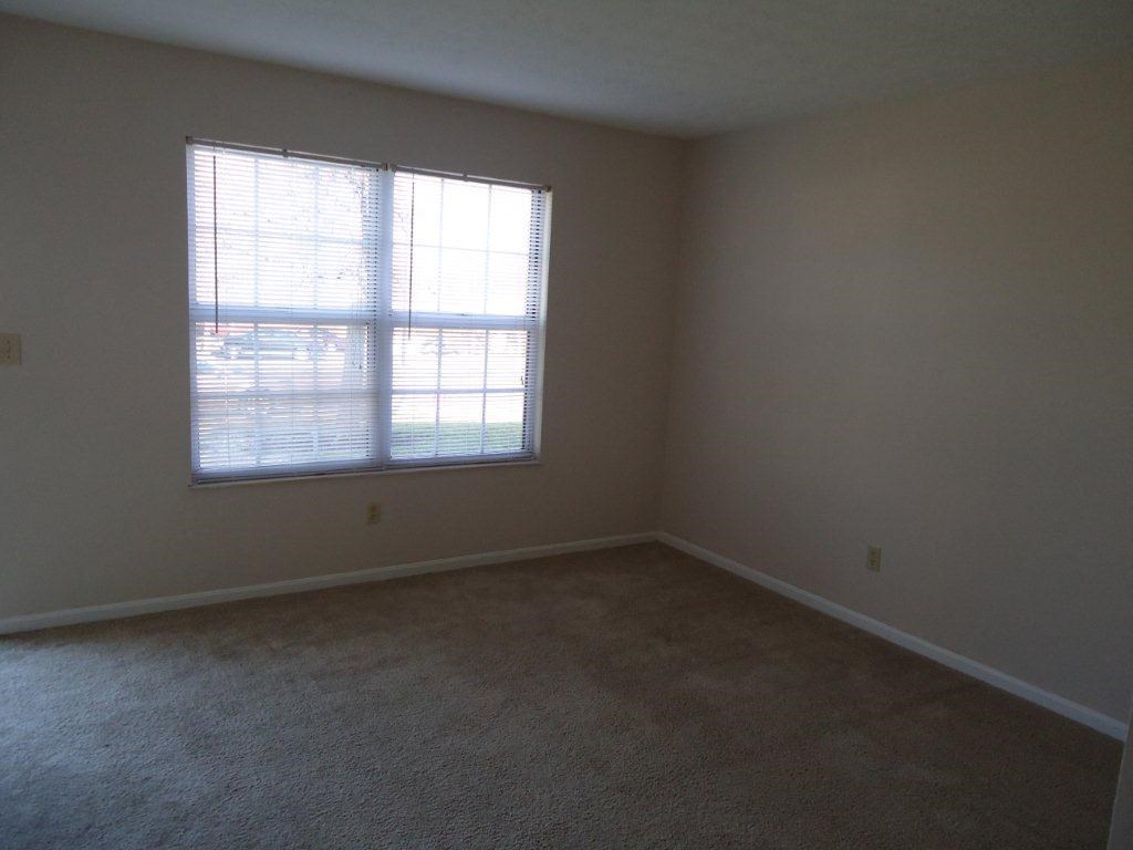 an empty room with a window and carpet