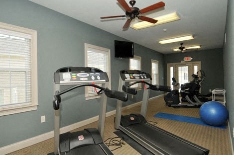 a gym with exercise equipment and a ceiling fan