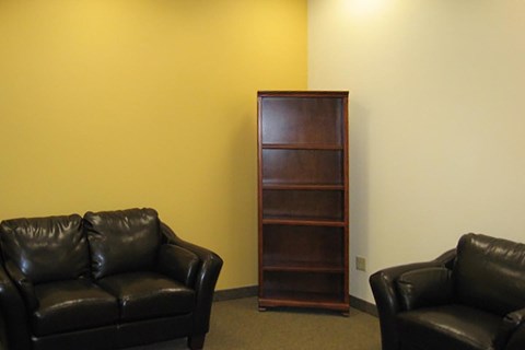 a living room with leather couches and a bookshelf
