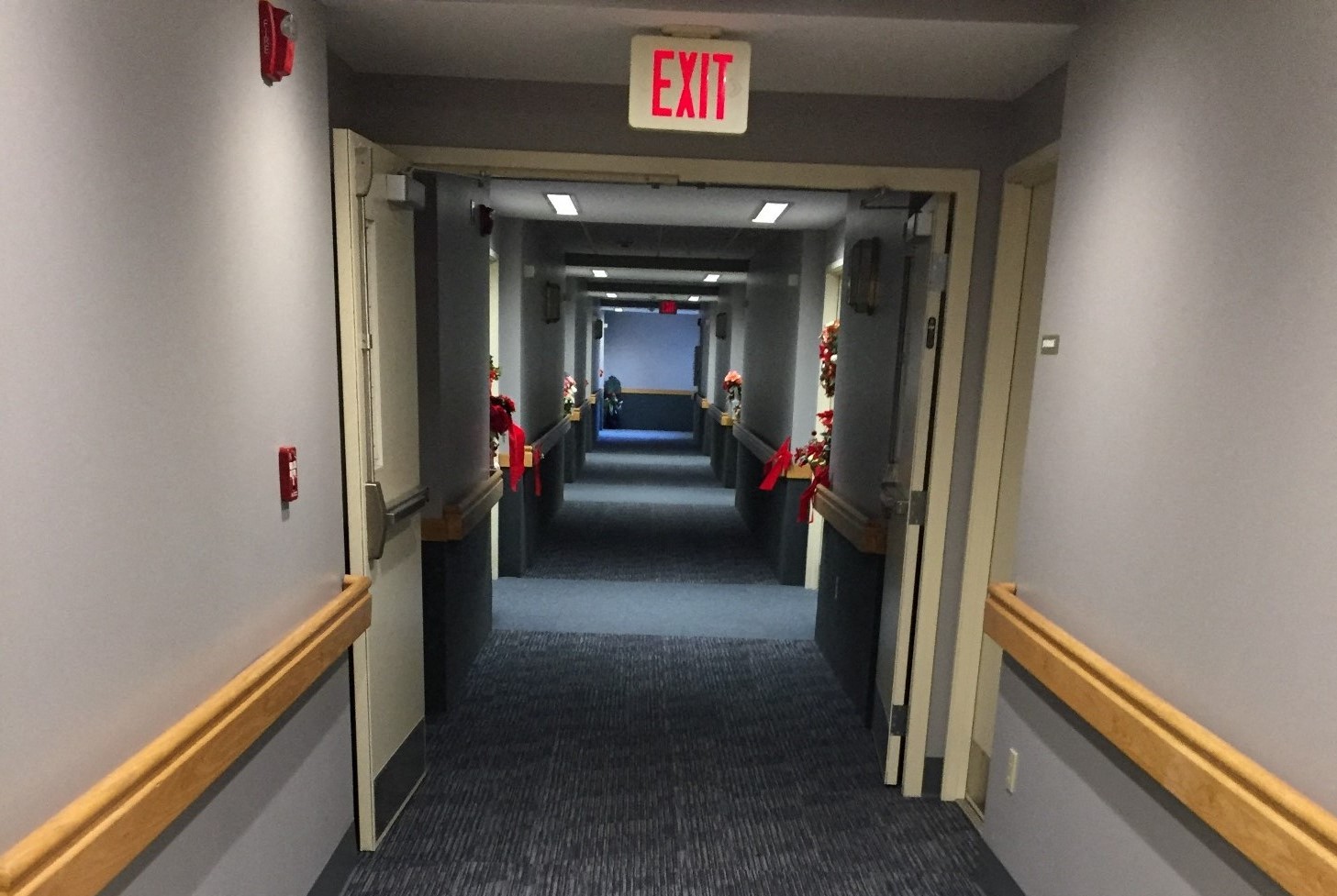 the hallway of an office with an exit sign on the ceiling and a long hallway
