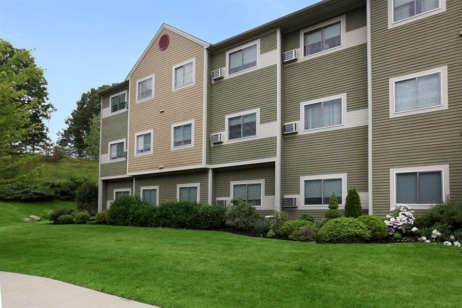 a large apartment building with a green lawn