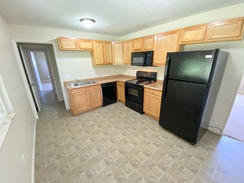 an empty kitchen with black appliances and wooden cabinets