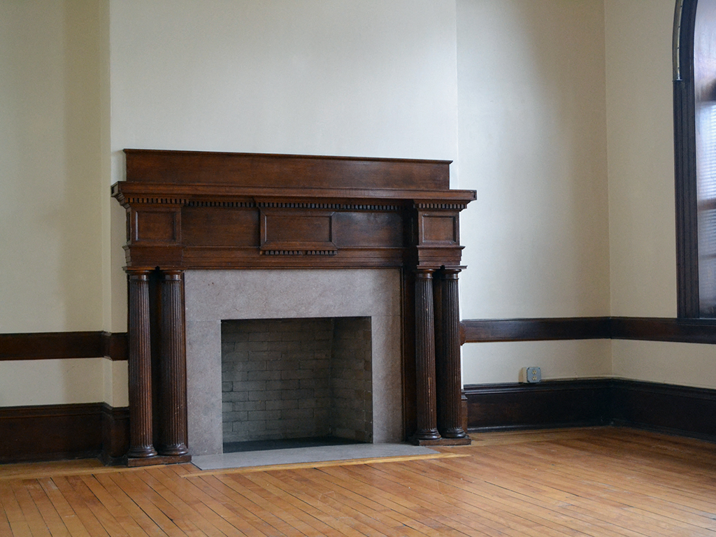 the fireplace in the corner of a room with a wooden floor