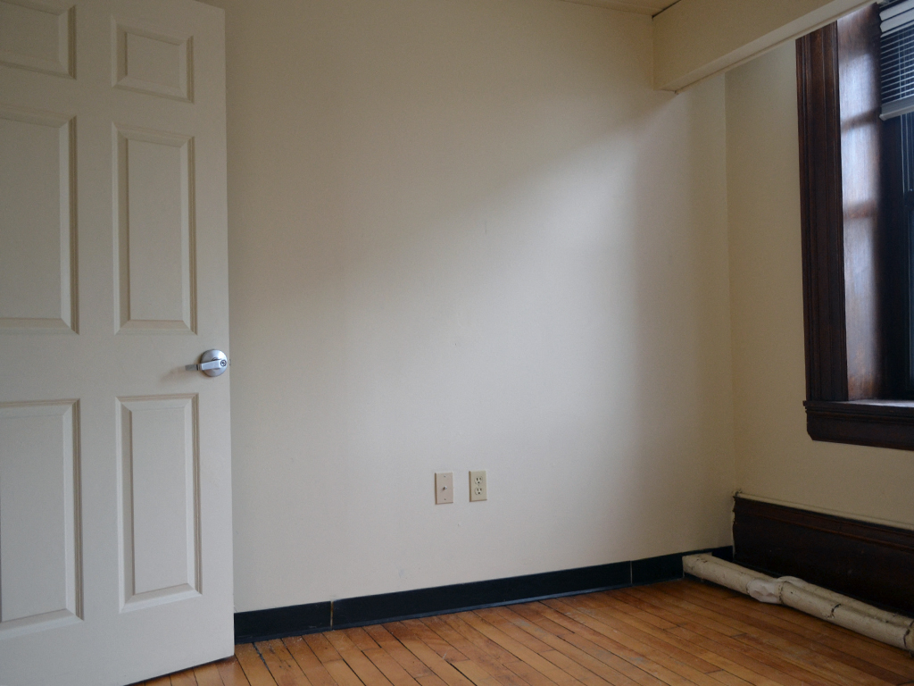 an empty room with a white door and a wood floor