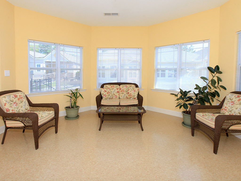 a living room with three chairs and potted plants