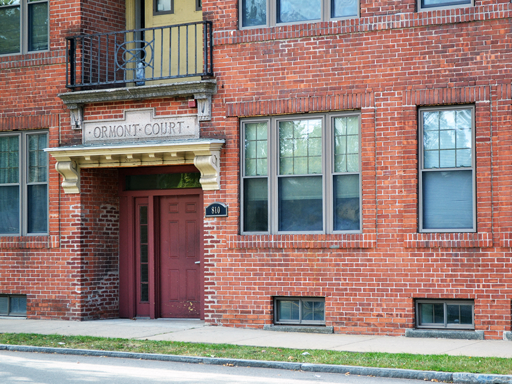 the front of a brick building with a red door