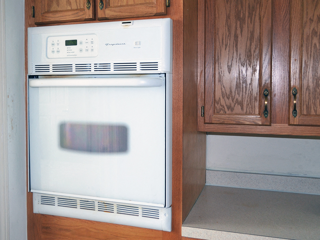 a kitchen with wooden cabinets and a white stove and oven