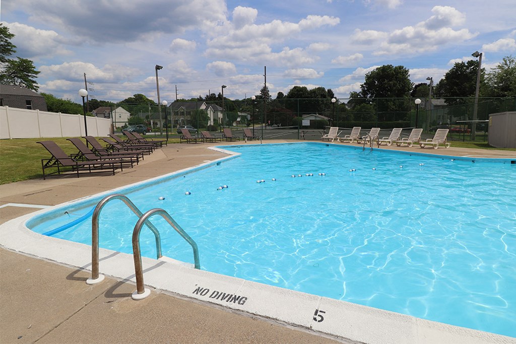 a swimming pool with chaise lounge chairs and a fence around it