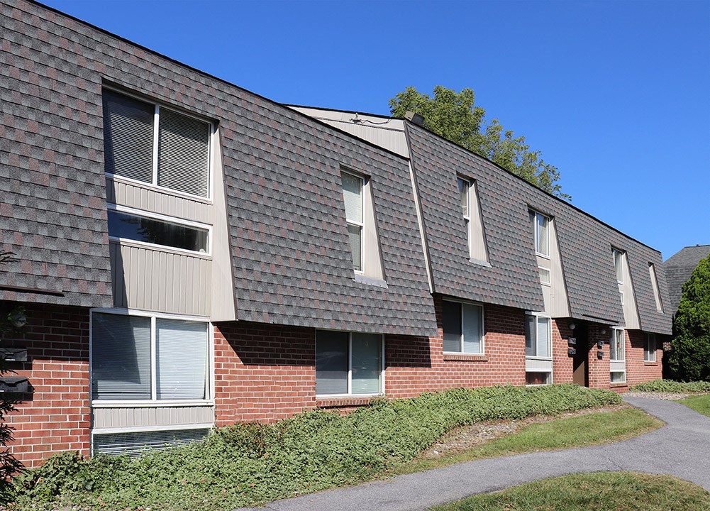 a brick apartment building with a sidewalk in front of it