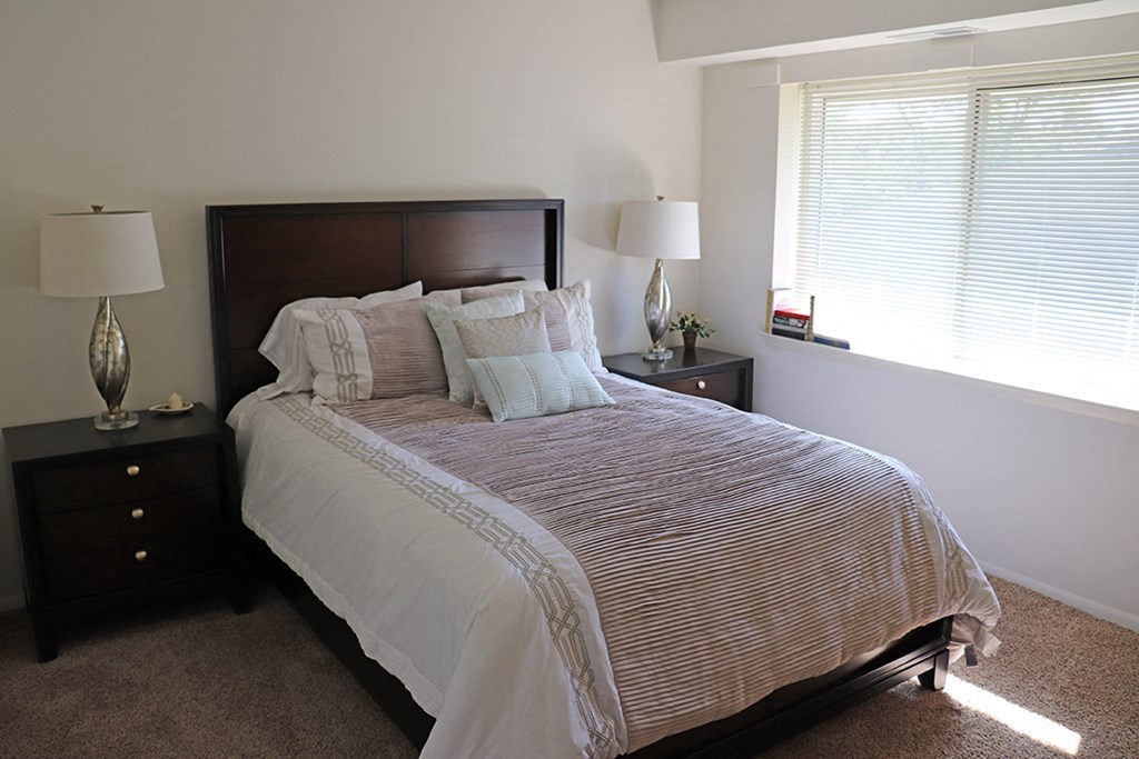 a bedroom with a bed and two night stands and a window