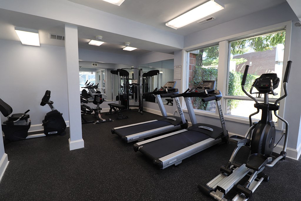 a gym with cardio equipment and windows in a building