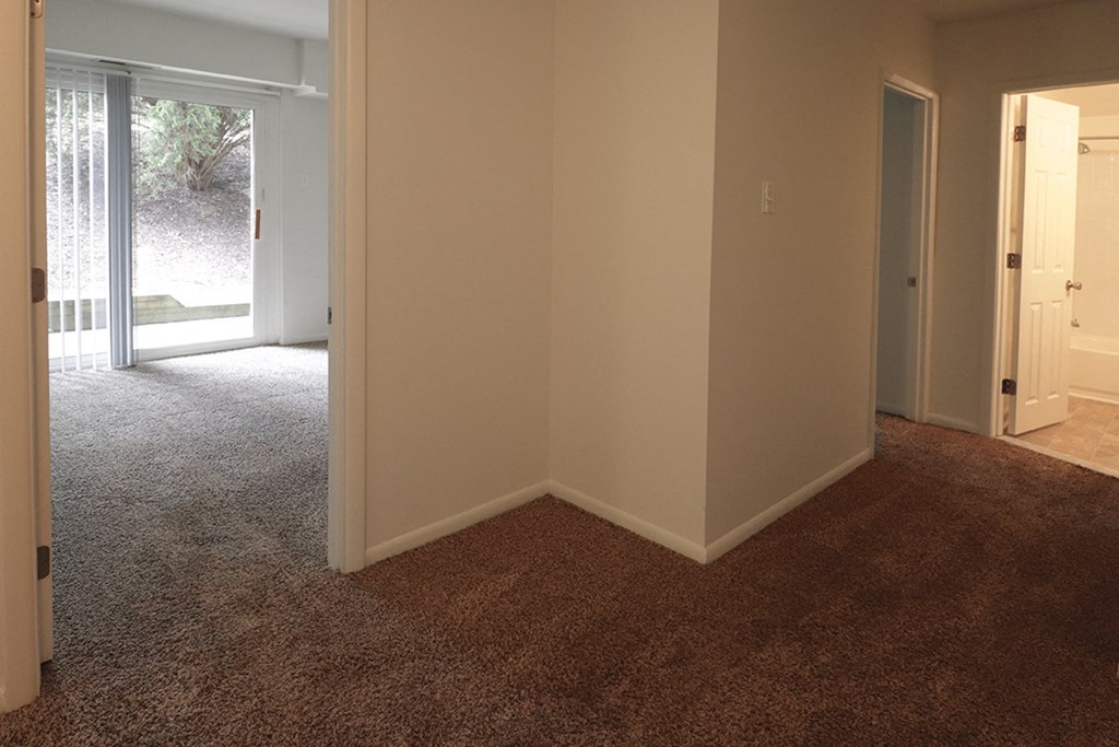 a living room with a carpeted floor and a door to a bedroom