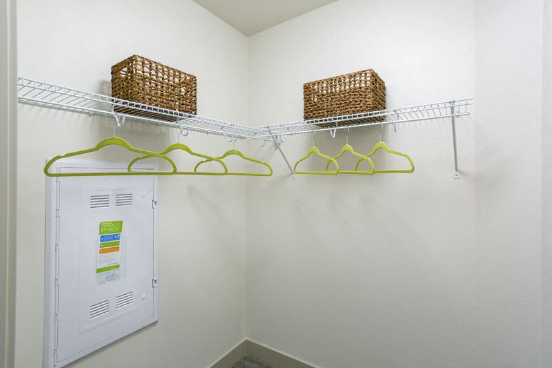 a closet with baskets and a dryer on the wall
