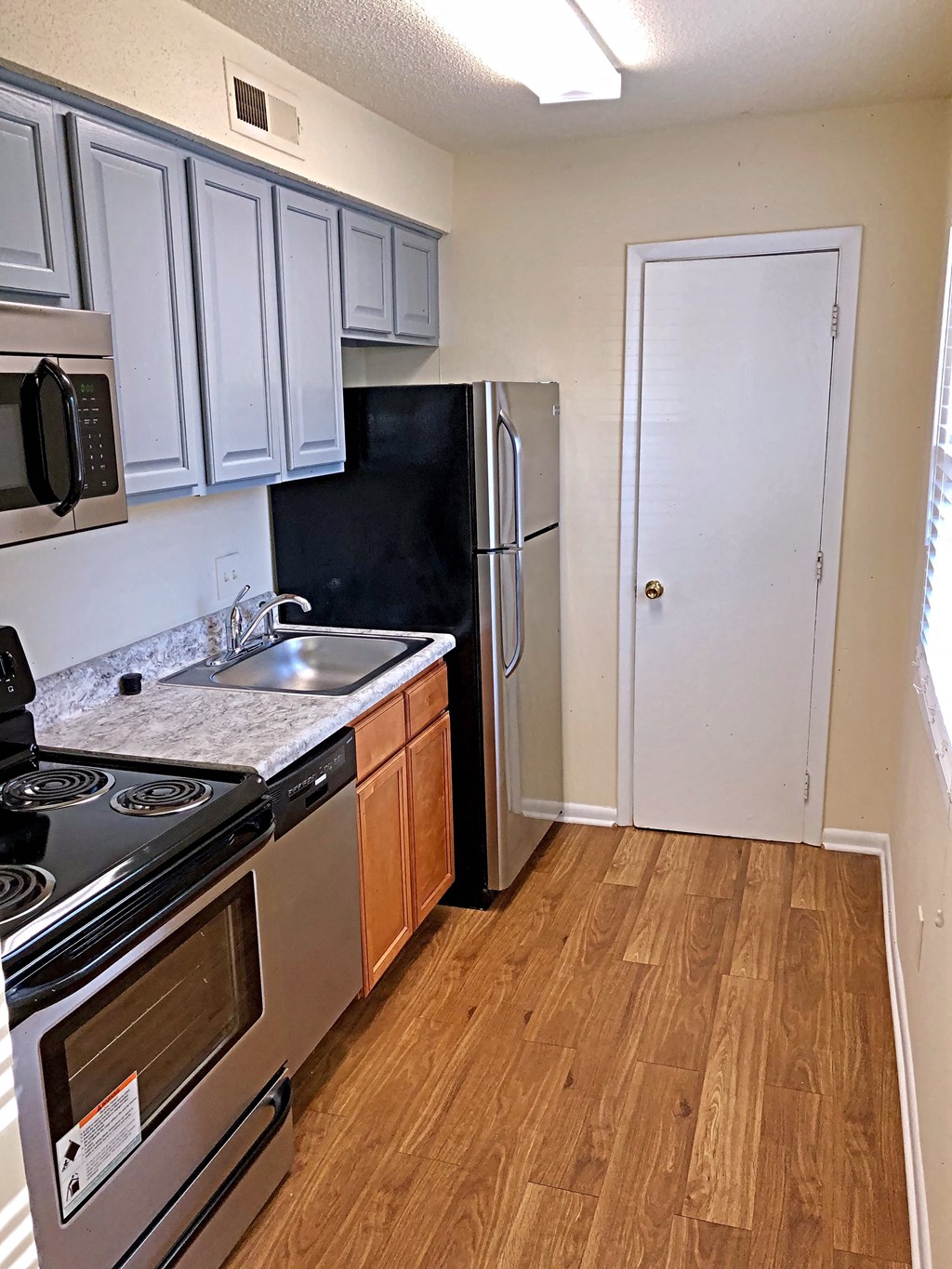 an empty kitchen with stainless steel appliances and white cabinets