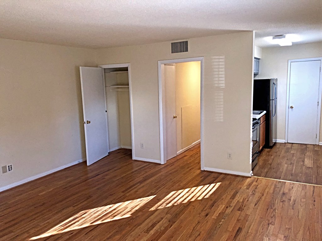 an empty living room with wood floors and a closet