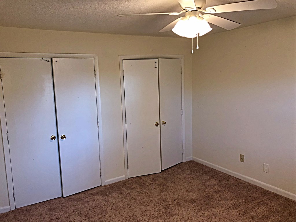 a bedroom with three closets and a ceiling fan