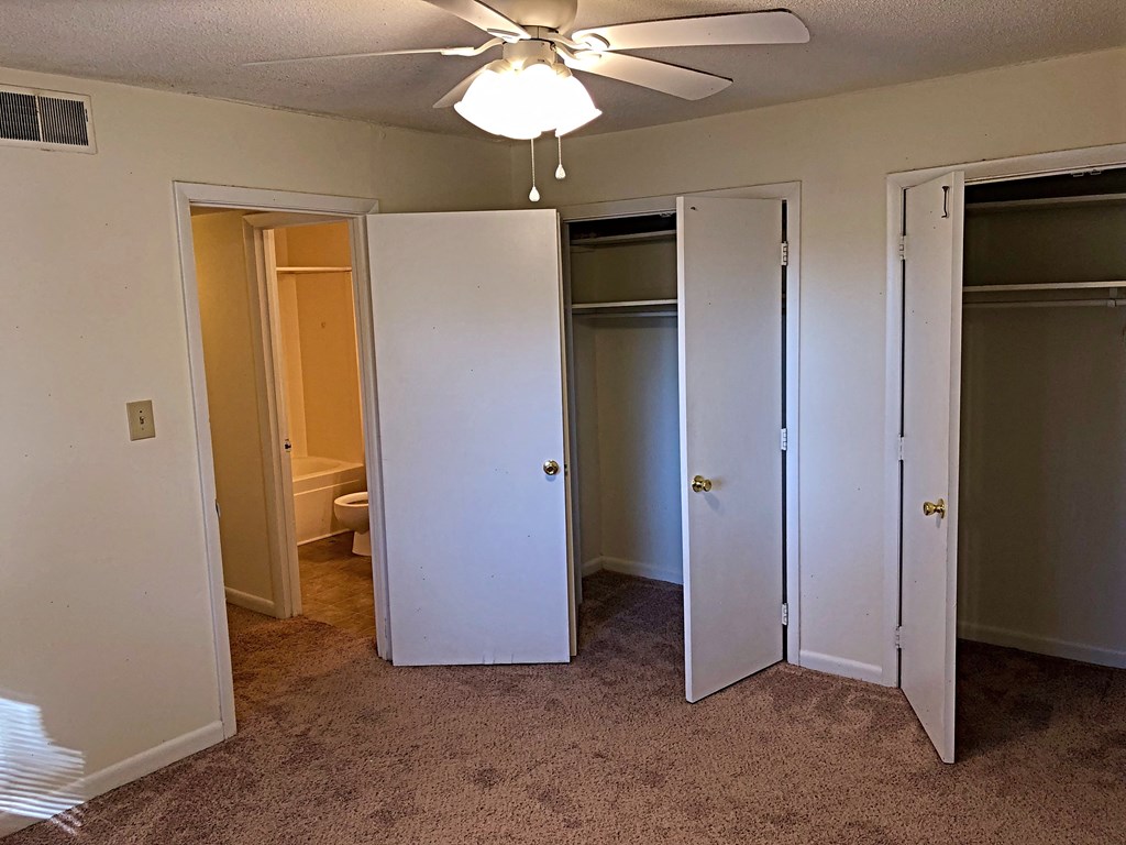 a bedroom with three closets and a ceiling fan