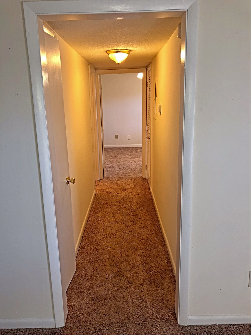 a hallway with an open door and a light on the ceiling