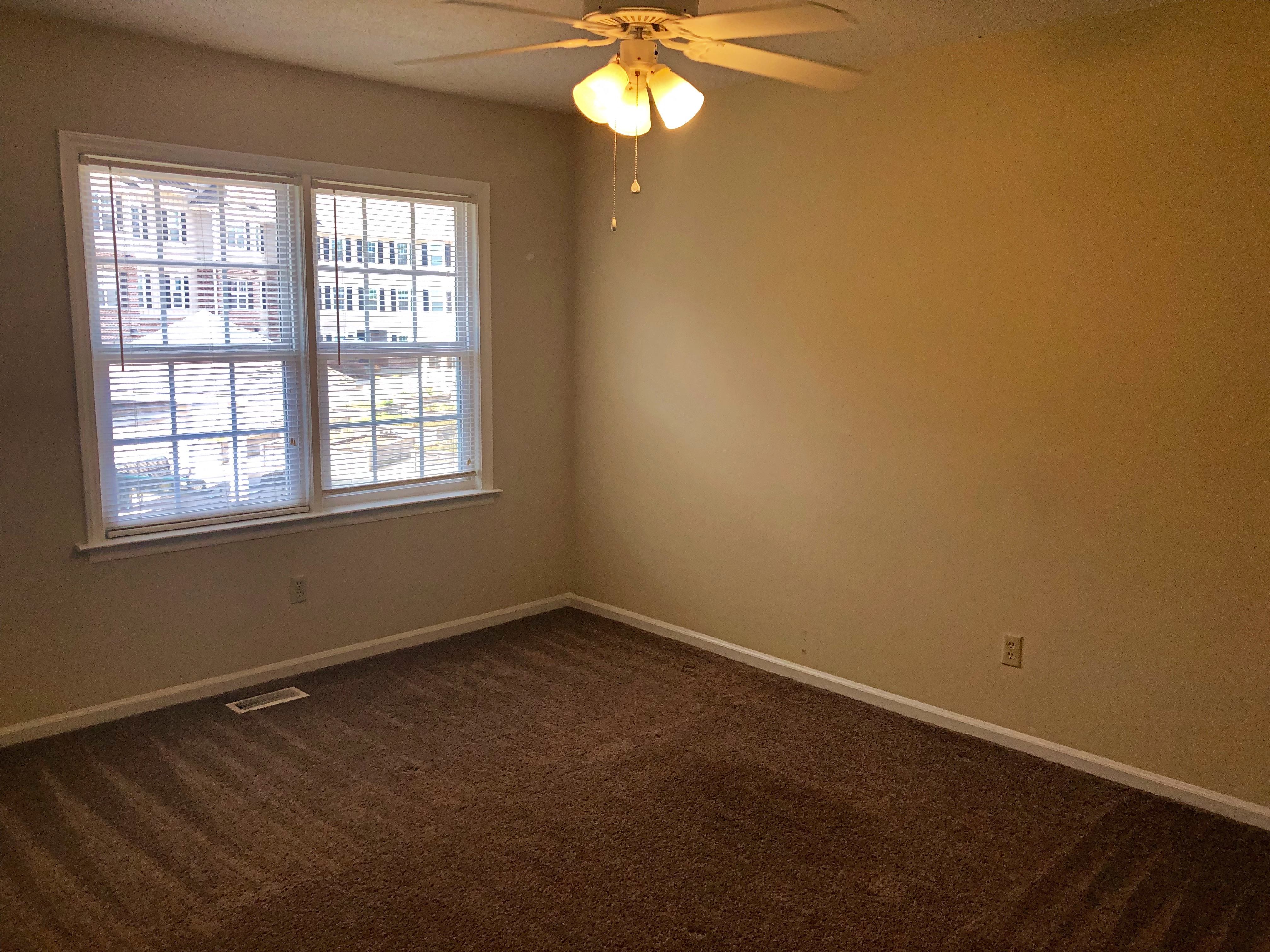 A room with a ceiling fan and a window.