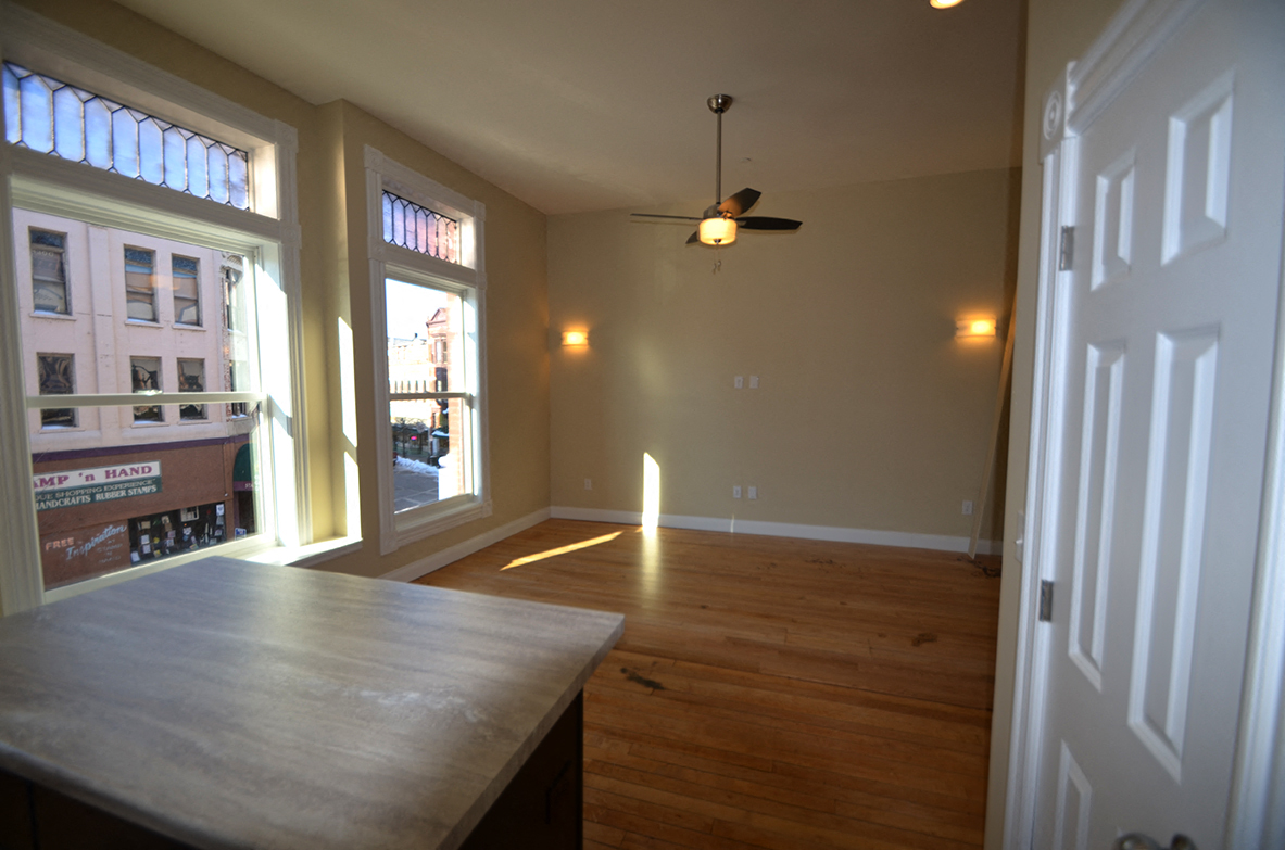 an empty living room with wood floors and a ceiling fan