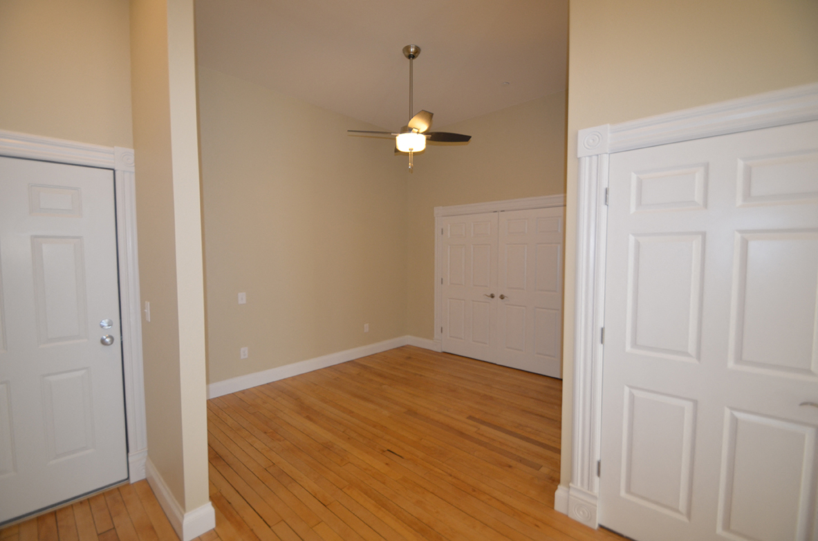 an empty living room with wood floors and a ceiling fan