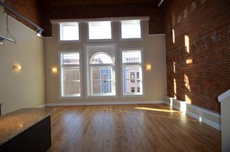 an empty living room with large windows and wood floors