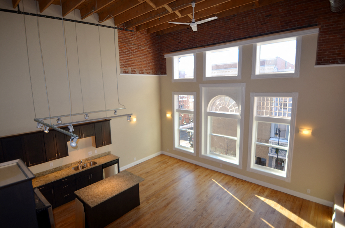 an open kitchen and living room with large windows and wood floors