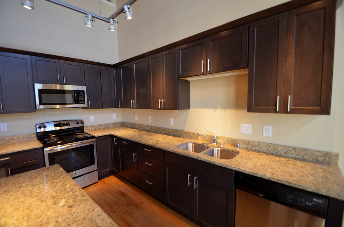 a kitchen with granite counter tops and dark wood cabinets