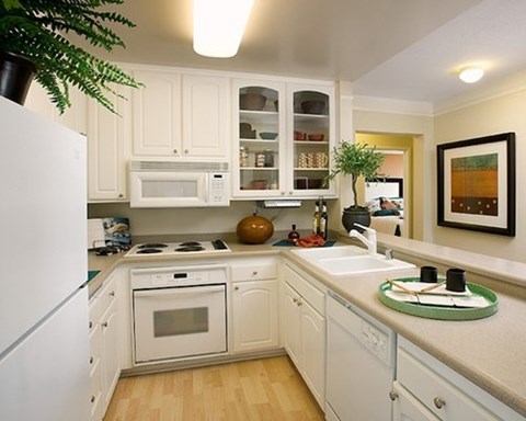 A kitchen with white cabinets and appliances.
