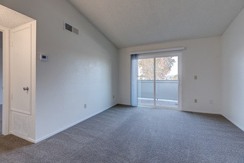 an empty living room with a door to a balcony