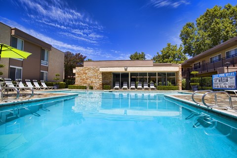 A swimming pool with chairs around it and a building in the background.