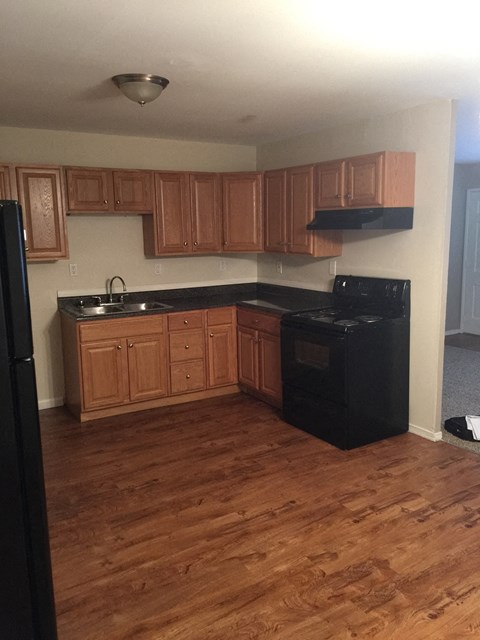 A kitchen with wooden cabinets and black appliances.