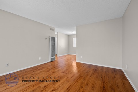 the living room of an apartment with wood flooring and white walls