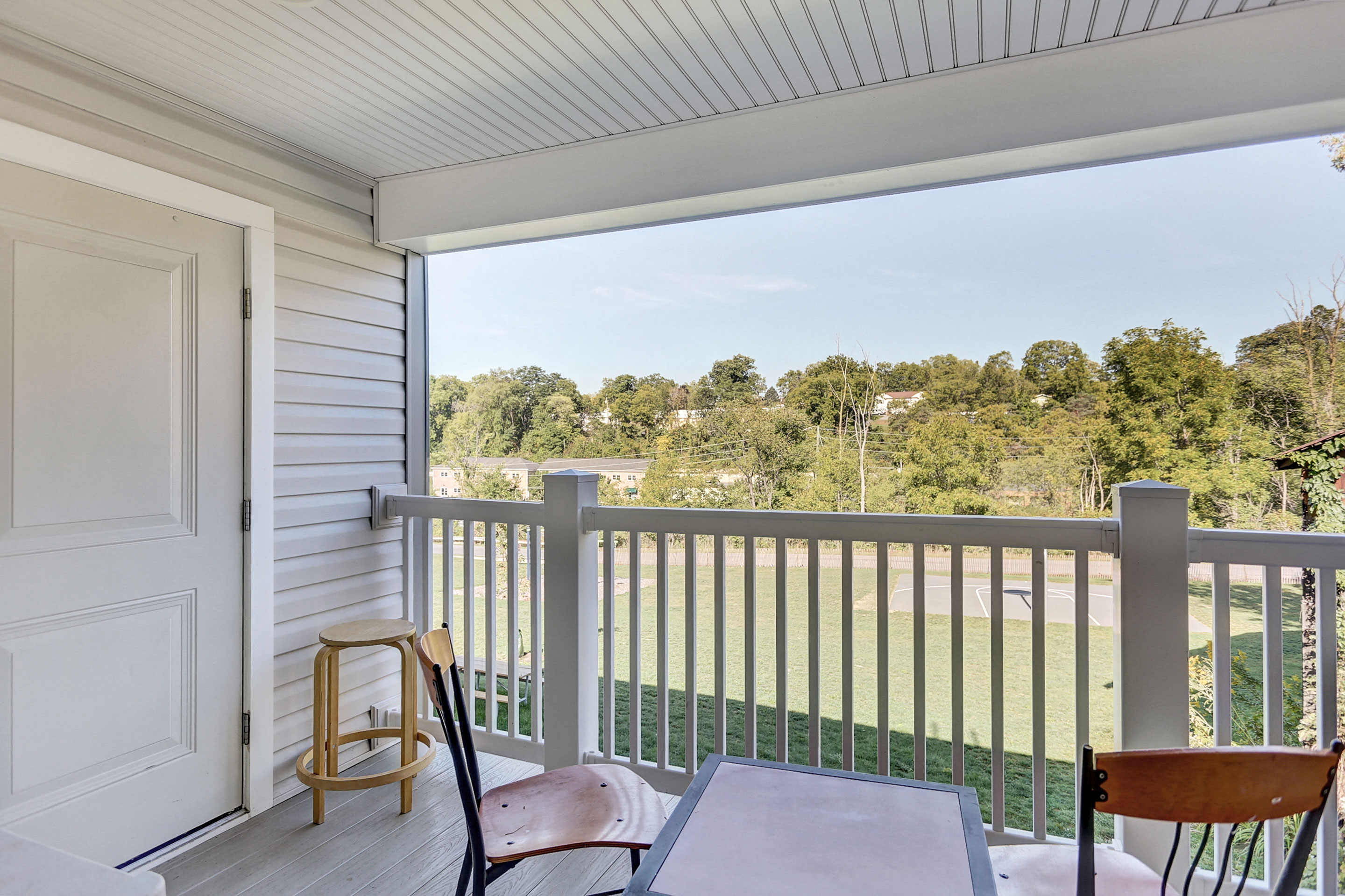 two chairs and a table on a balcony with a view of trees