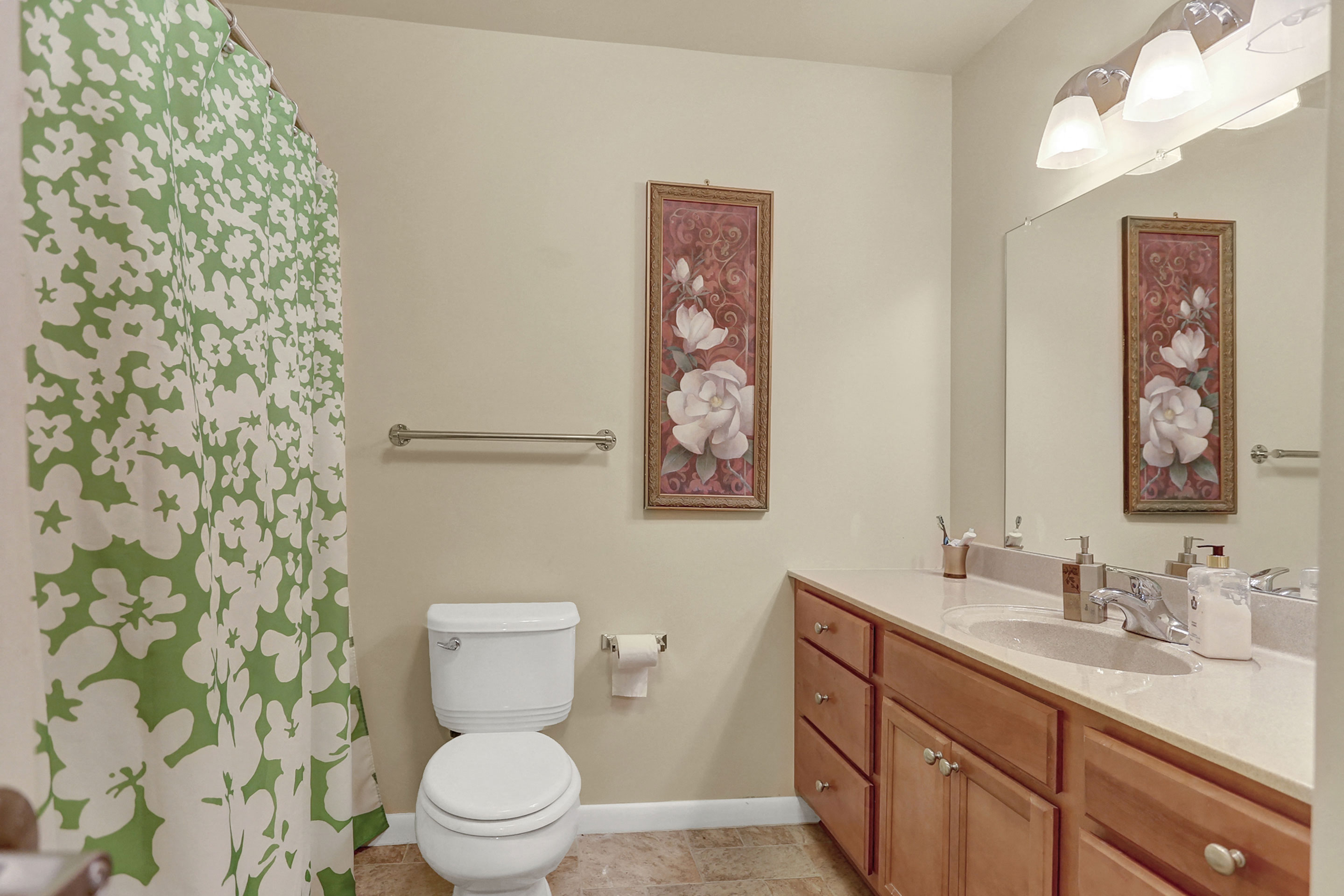 a bathroom with a green and white shower curtain and a toilet and sink