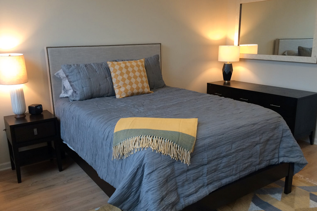 a bedroom with a bed and two nightstands and a mirror