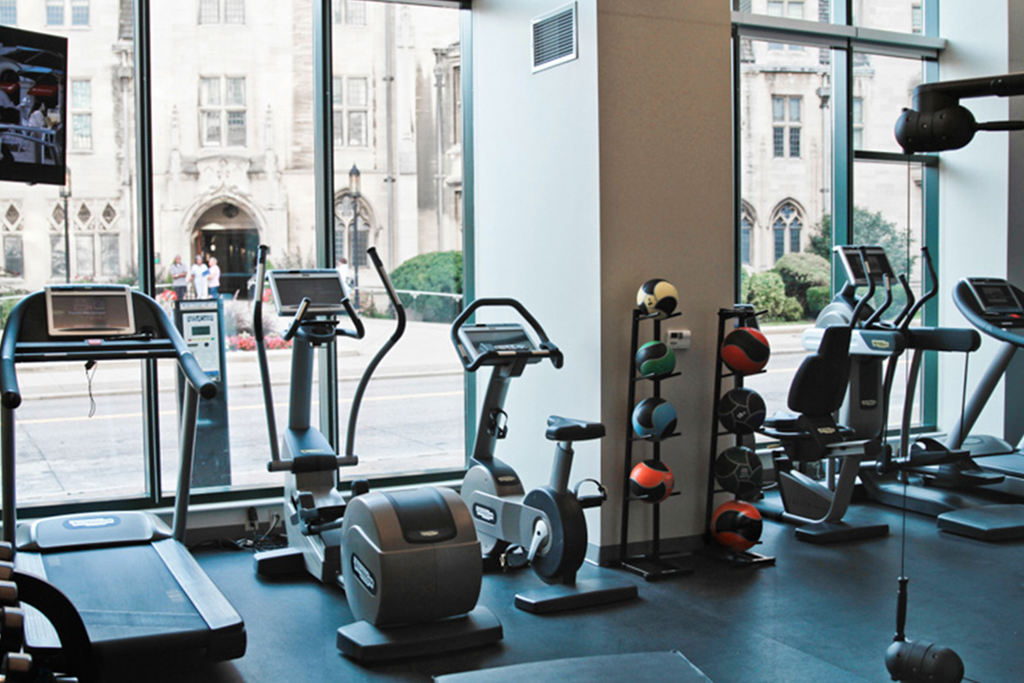 a gym full of exercise equipment in front of a window