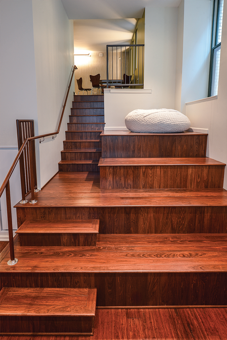 a bed on the top of a wooden staircase in a house