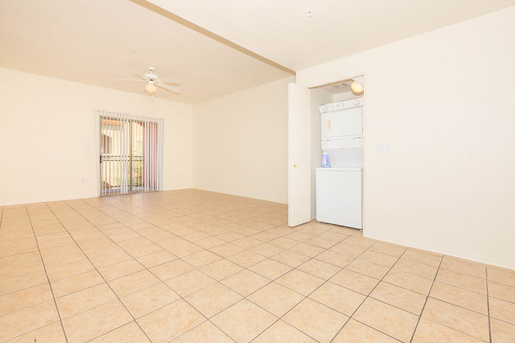 an empty living room with tile flooring and a white refrigerator