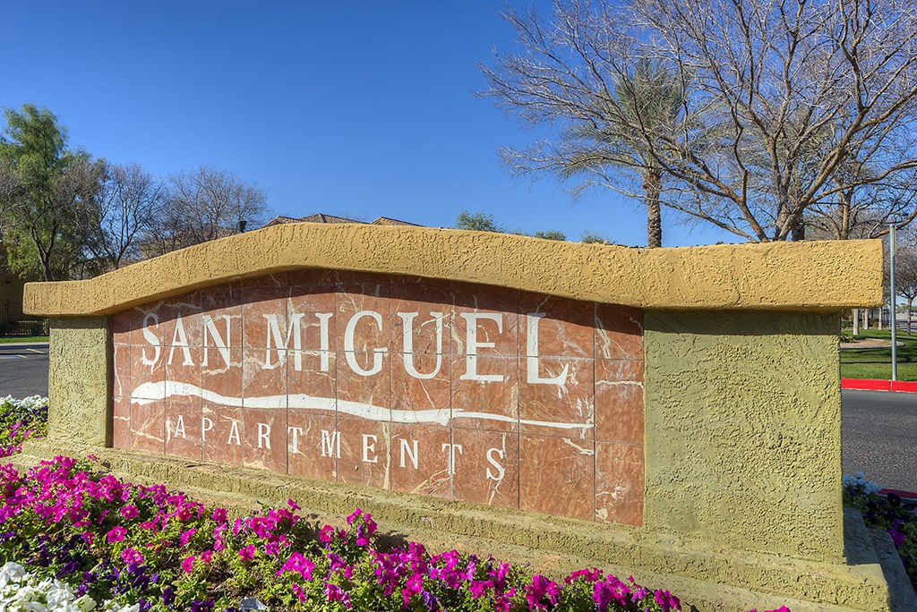 a sign apartments in front of flowers