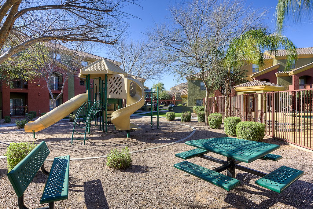 a playground with a slide and picnic tables